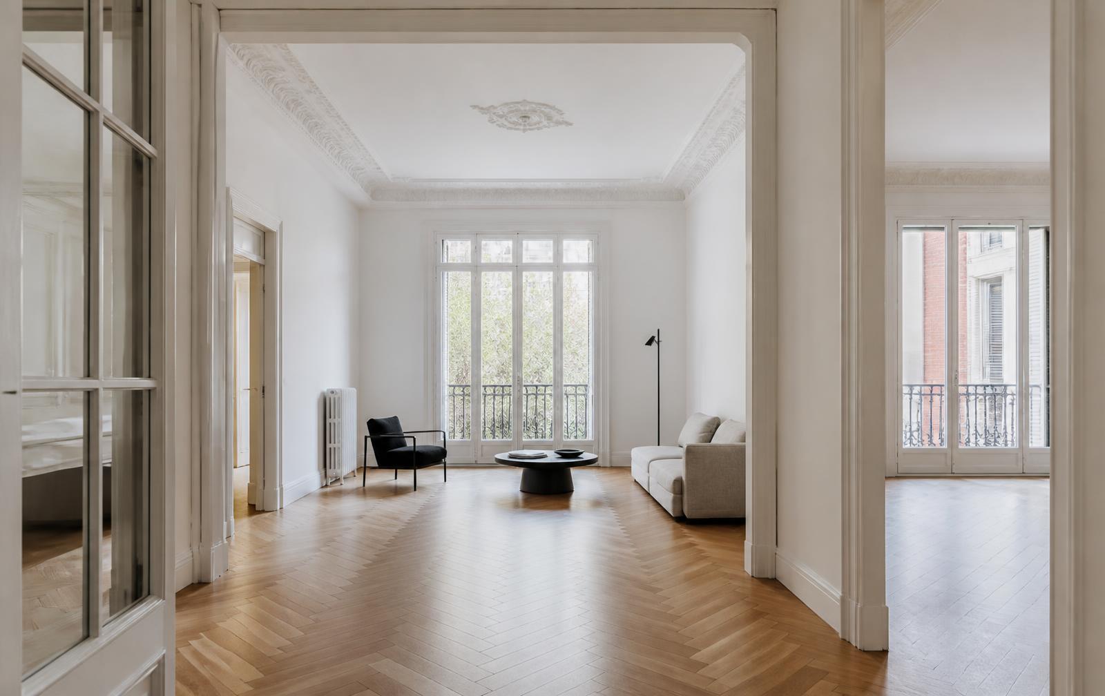 Interior reformado de una vivienda madrileña con techos altos, suelo de espiga y luz natural